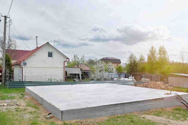 Placă de fundație din beton turnat pentru o construcție planificată într-o grădină.
