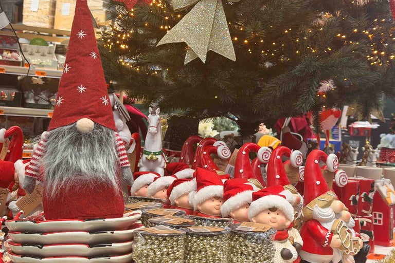 Decorațiuni de Crăciun cu figurine spiriduși și ornamente în magazinul Hornbach, prezentate în fața unui brad de Crăciun iluminat.