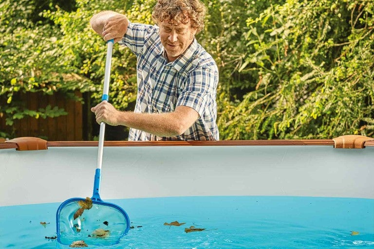Bărbat curățând piscina cu o plasă.