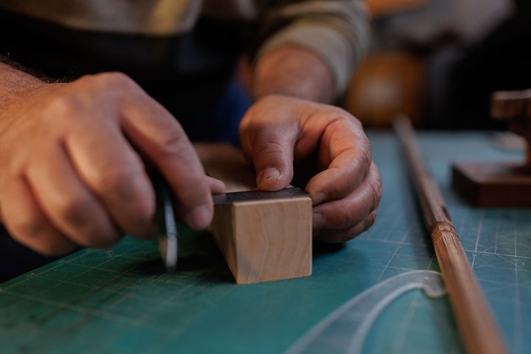 Artizan măsoară o bucată de lemn cu o riglă