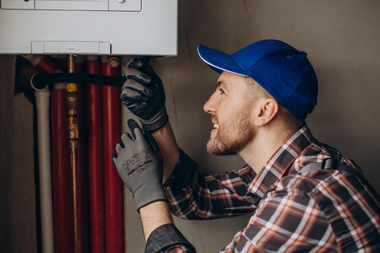 Un instalator lucrează la un sistem de încălzire cu țevi.