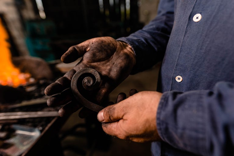 Fierar ține o piesă de prelucrat spiralată în mâini