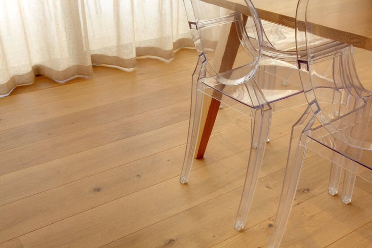 Scenă cu podea din lemn, scaune transparente și perdea