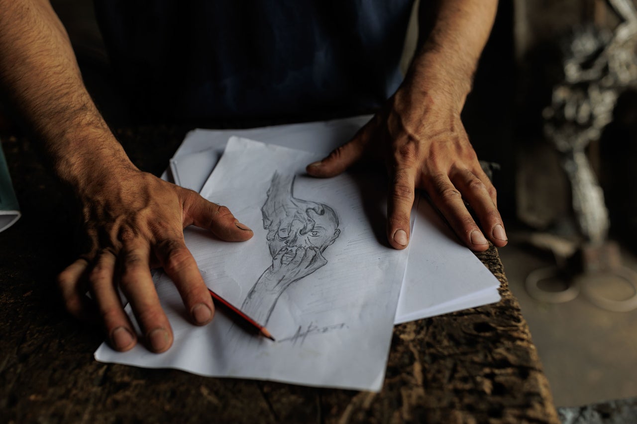 Un bărbat desenează o schiță a unei fețe cu un creion pe hârtie.