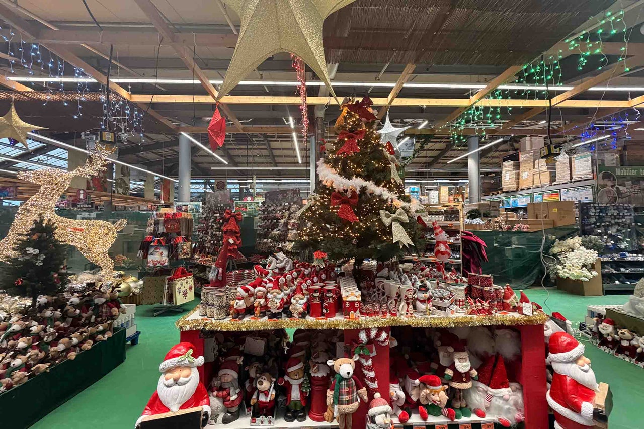 Decorațiuni de Crăciun în magazinul Hornbach cu brad de Crăciun, figurine luminoase, Moși Crăciun și iluminat festiv.