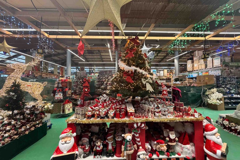 Decorațiuni de Crăciun în magazinul Hornbach cu brad de Crăciun, figurine luminoase, Moși Crăciun și iluminat festiv.