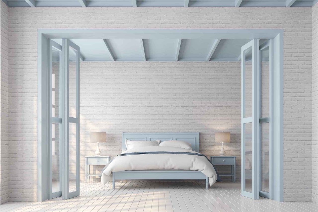 Dormitor luminos cu perete de cărămidă, pat și noptiere