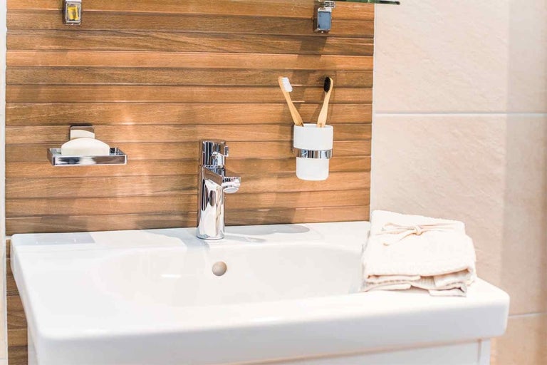 Chiuvetă cu baterie, savonieră, pahar pentru periuțe de dinți și prosoape în baie