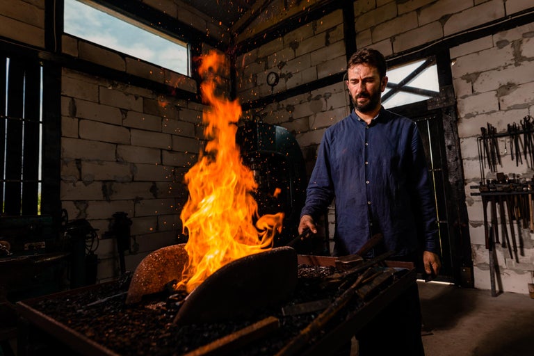 Fierar lucrând cu un cuptor de forjă într-un atelier