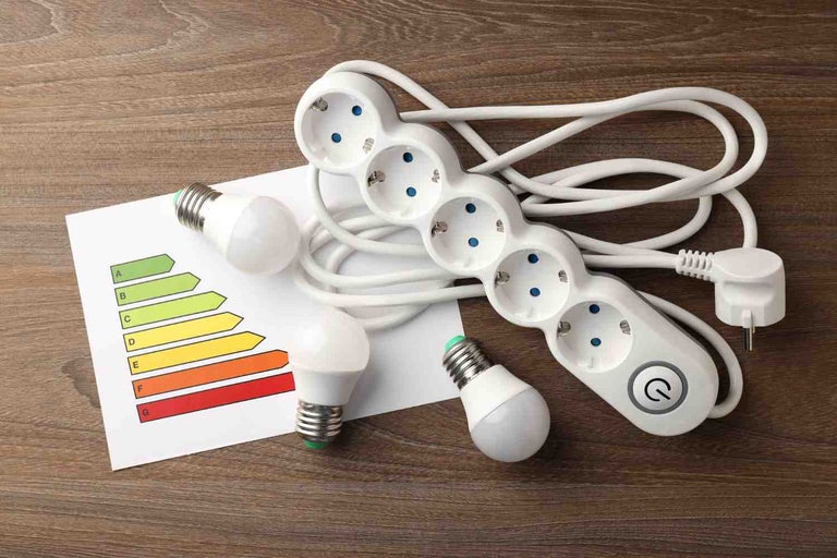 Ștecăr multiplu, becuri LED și etichetă de eficiență energetică pe o masă