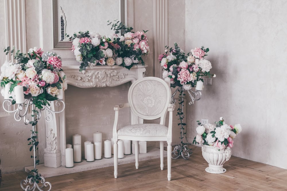 Scenă decorativă cu scaun, șemineu, oglindă, lumânări și aranjamente florale pentru un interior elegant