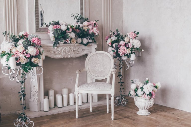 Scenă decorativă cu scaun, șemineu, oglindă, lumânări și aranjamente florale pentru un interior elegant