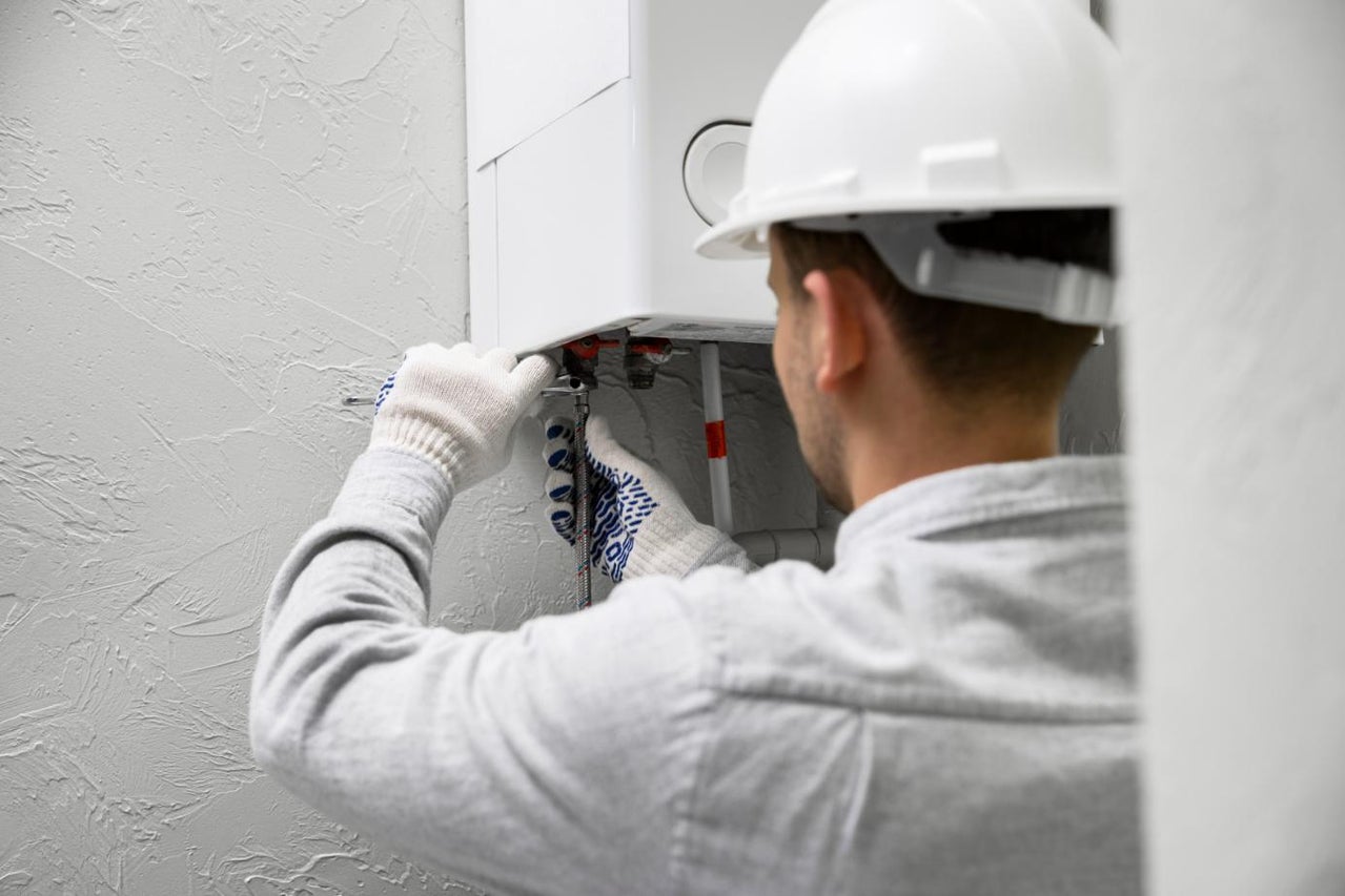 Instalator cu cască de protecție montează centrala termică