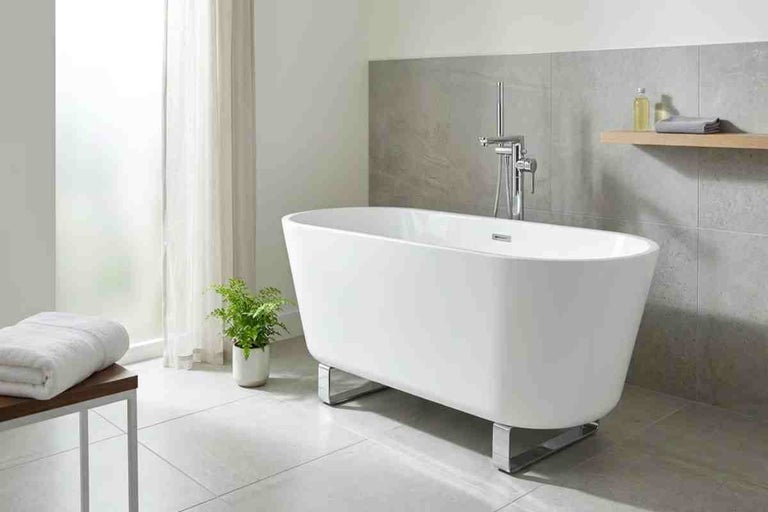 Cadă de baie de sine stătătoare într-o baie modernă cu baterie stativă și faianță gri.