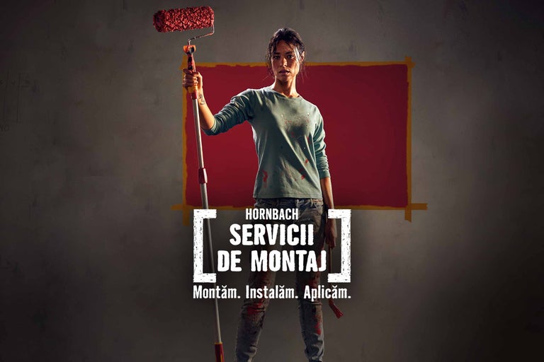 Femeie cu trafalet în fața unui perete vopsit în roșu pentru serviciul de montaj Hornbach