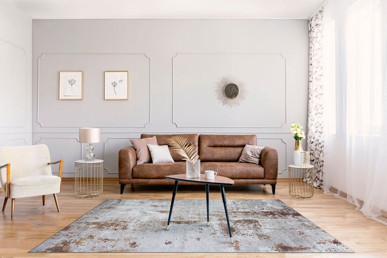 Living cu canapea din piele maro, fotoliu, covor și măsuțe laterale