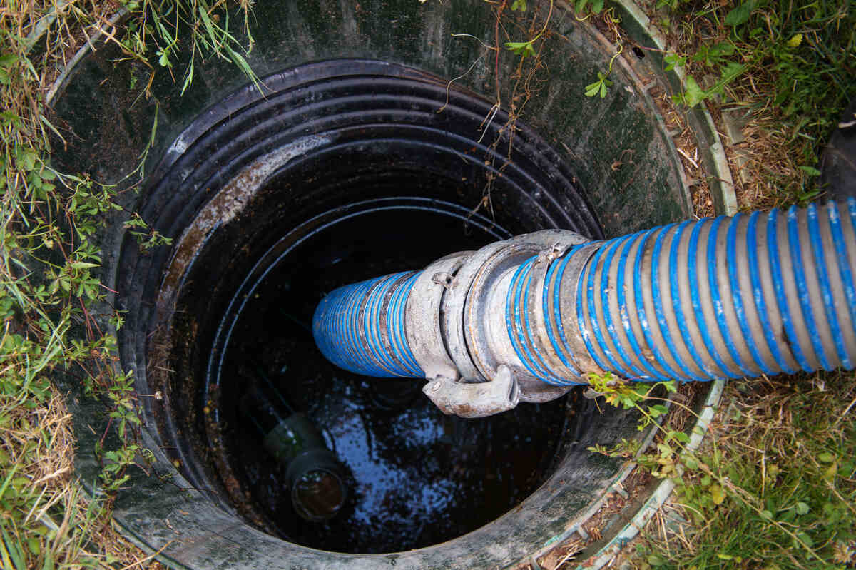 Fosă septică deschisă cu furtun albastru pentru evacuarea apelor uzate