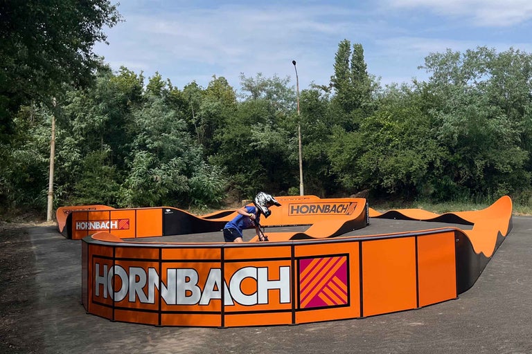 Copil pe un pumptrack cu sigla Hornbach în aer liber