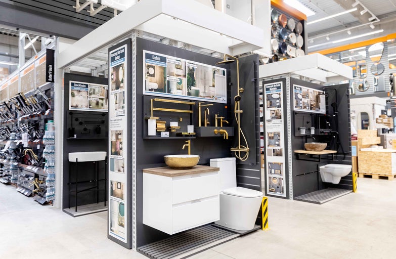 Expoziție de seturi de baie în magazinul Hornbach cu chiuvete, robinete și toalete