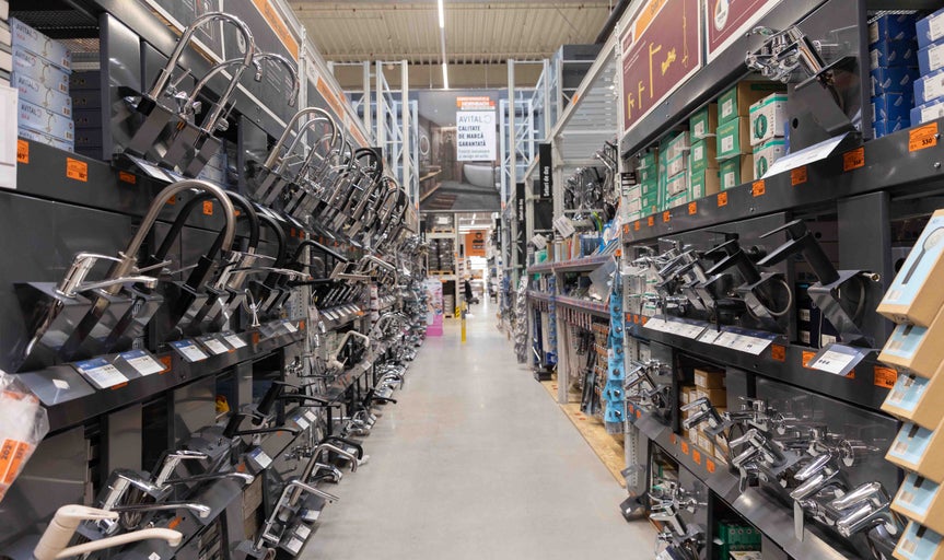 Vedere spre culoar în magazinul Hornbach cu rafturi pline cu baterii de baie și accesorii