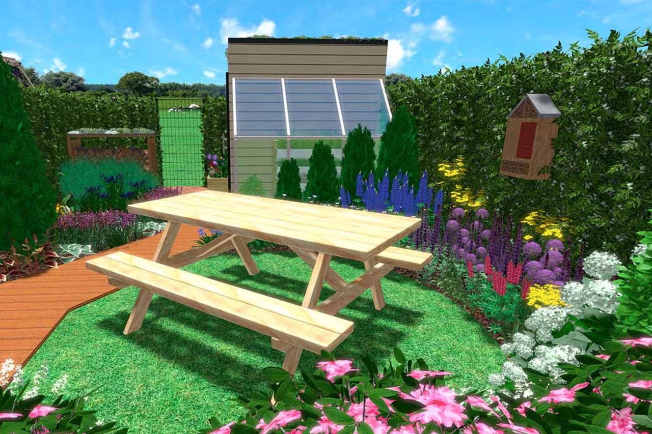Set de masă de picnic din lemn într-o grădină luminoasă și organizată, cu flori, gard viu, un hotel pentru insecte și o magazie de grădină.