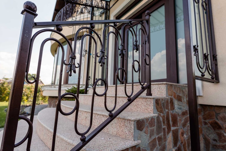 Scară cu balustradă metalică decorativă spre intrarea casei