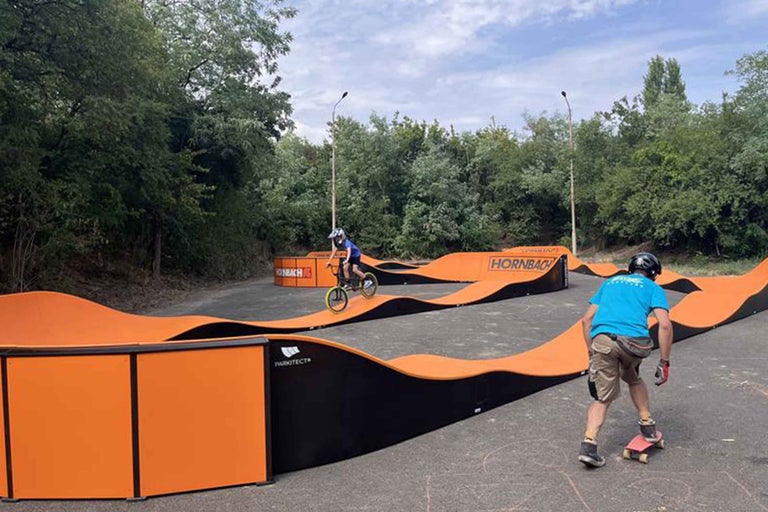 Copilul merge cu bicicleta pe un pumptrack cu logo-ul Hornbach.