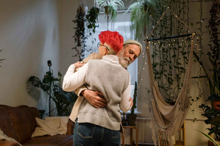 Îmbrățișare într-o cameră cu plante suspendate și un hamac