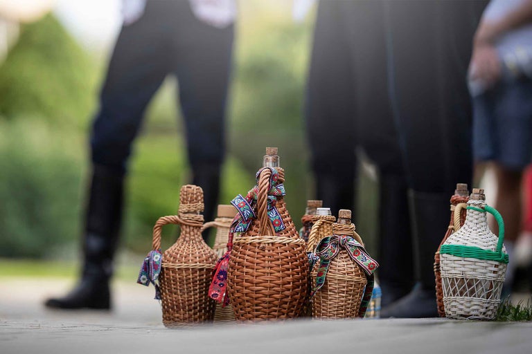 Sticle de vin decorative în coșuri împletite, împodobite cu panglici