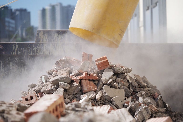 Un morman de moloz si praf, rezultat din demolari, la capatul unui tobogan pentru deseuri