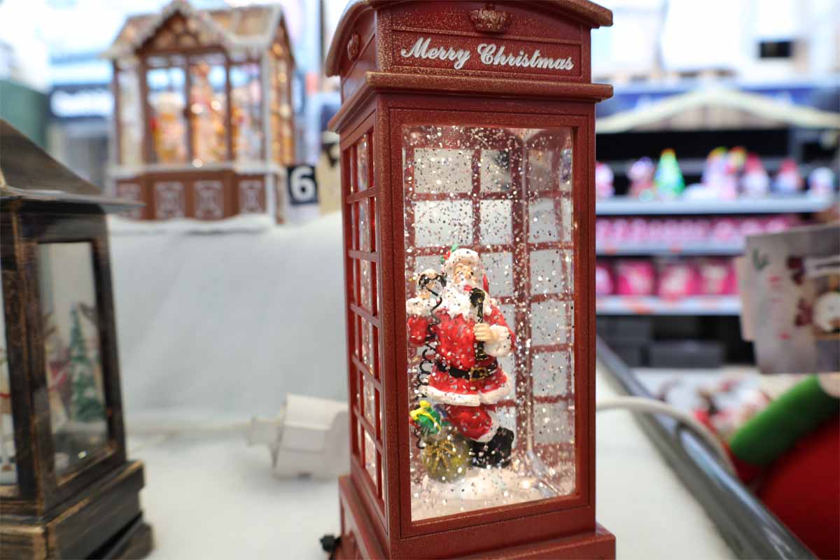Glob decorativ cu zăpadă în formă de cabină telefonică cu figurină Moș Crăciun.