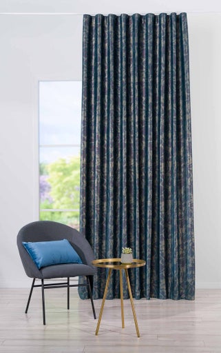 Cortină decorativă lângă un fotoliu și o măsuță laterală