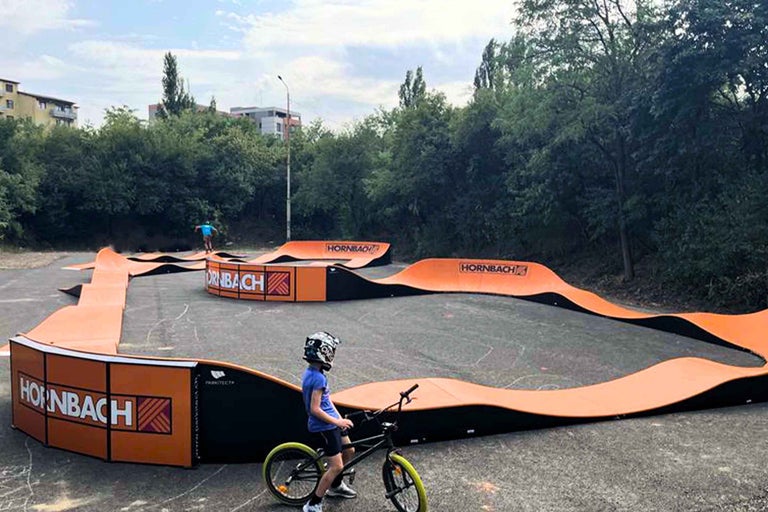 Copil cu bicicleta pe un pumptrack cu logo-ul Hornbach