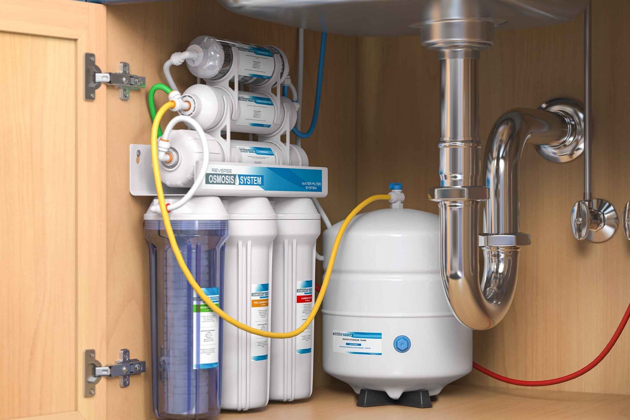 Sistem de filtrare a apei prin osmoză inversă instalat în masca de sub chiuvetă, cu cartușe de filtrare și rezervor de stocare a apei.