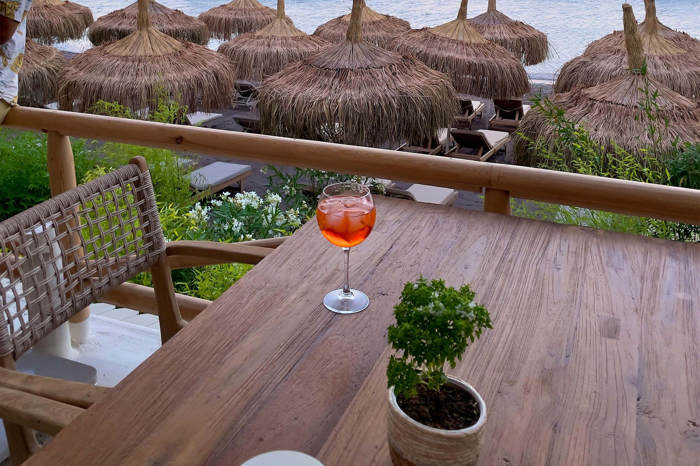 Scenă cu pahar de cocktail, plantă la ghiveci și umbrele de soare pe plajă