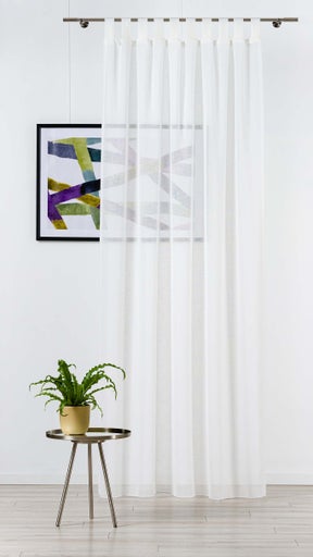 Cortină decorativă albă cu prindere cu bucle în fața unei ferestre, completată de o fotografie înrămată și o plantă de interior pe o măsuță laterală.