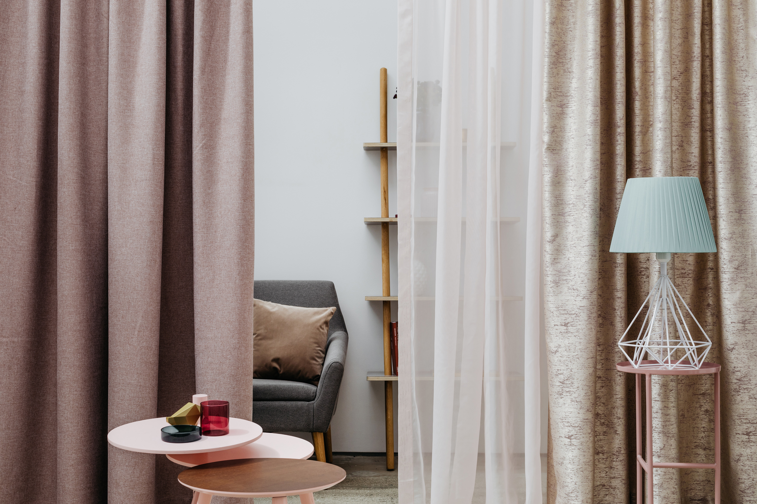 Living decorativ cu perdele, măsuțe laterale, fotoliu și rafturi pentru o atmosferă confortabilă