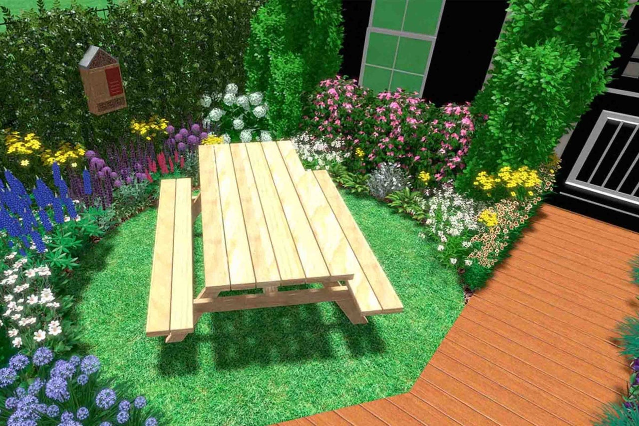 Masă de picnic din lemn cu bănci integrate într-o grădină înflorită lângă o terasă din lemn.