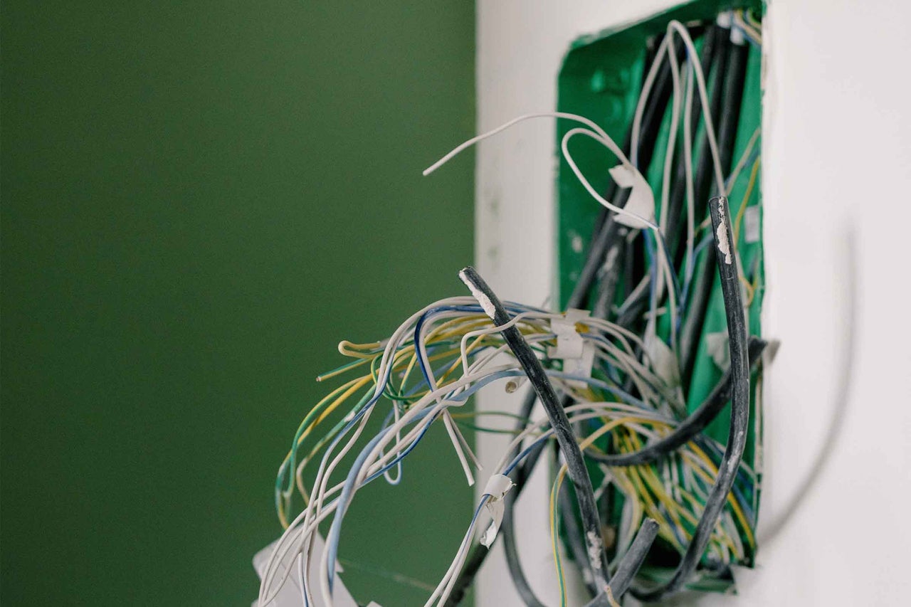 Doză de perete deschisă cu numeroase cabluri electrice și fire pentru instalația electrică.