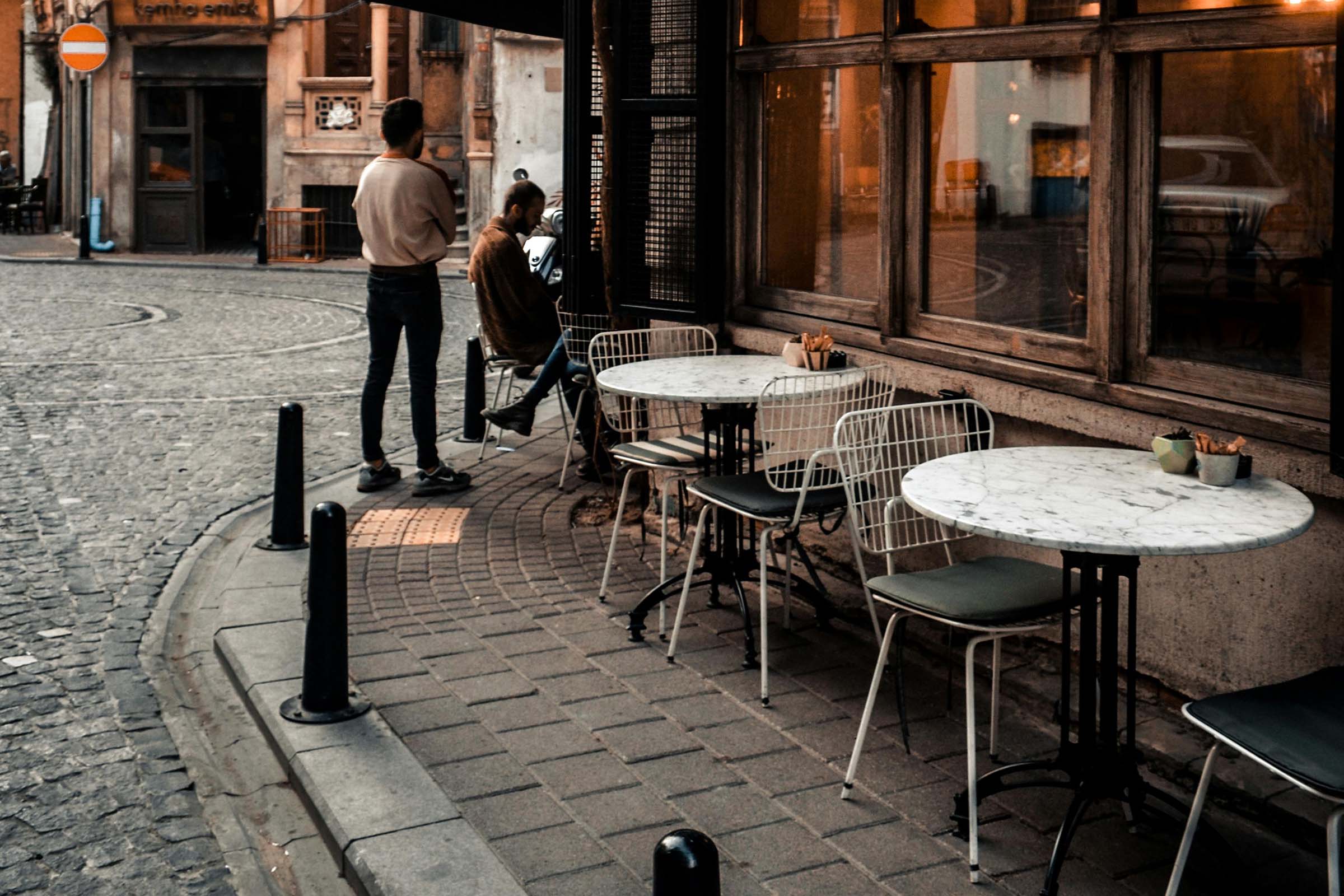 Exteriorul unei cafenele cu mese și scaune pe un trotuar