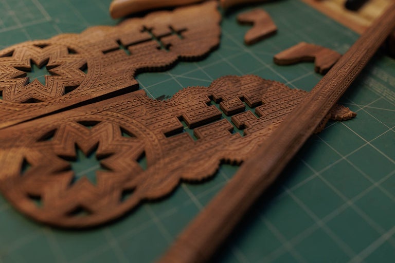 Elemente din lemn sculptat cu stele și modele pe un suport de tăiat.