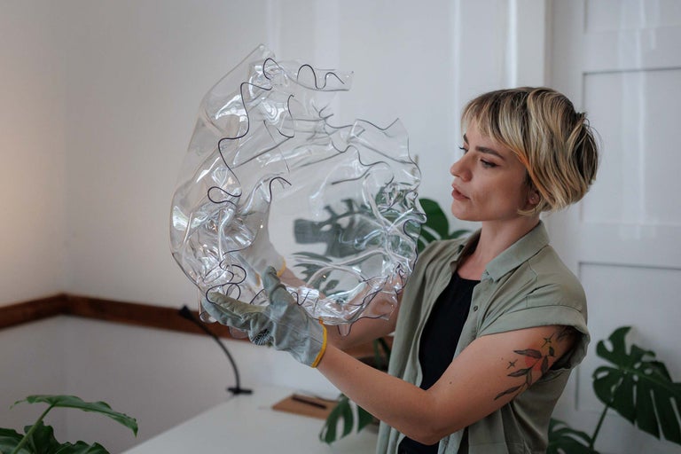 O femeie se uită la un element din plastic transparent, ondulat, cu o margine neagră.
