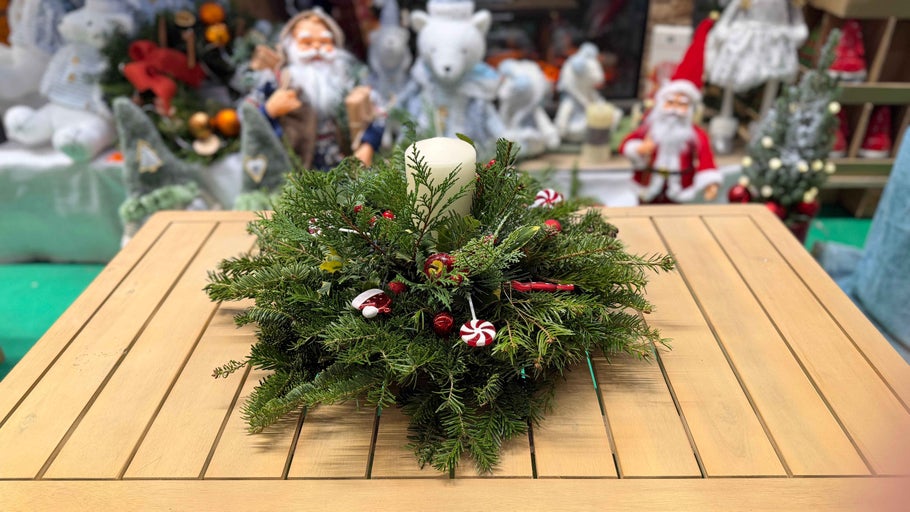 Aranjament decorativ cu lumânare și decorațiuni de Crăciun pe o masă