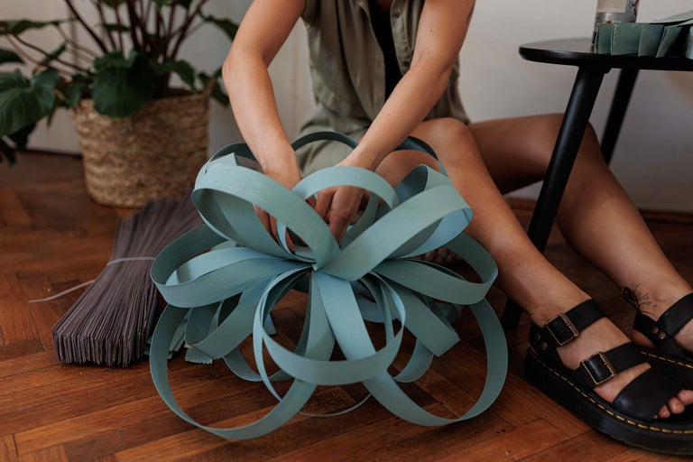 Femeie care modelează decorațiuni din fâșii de hârtie pe podea de lemn