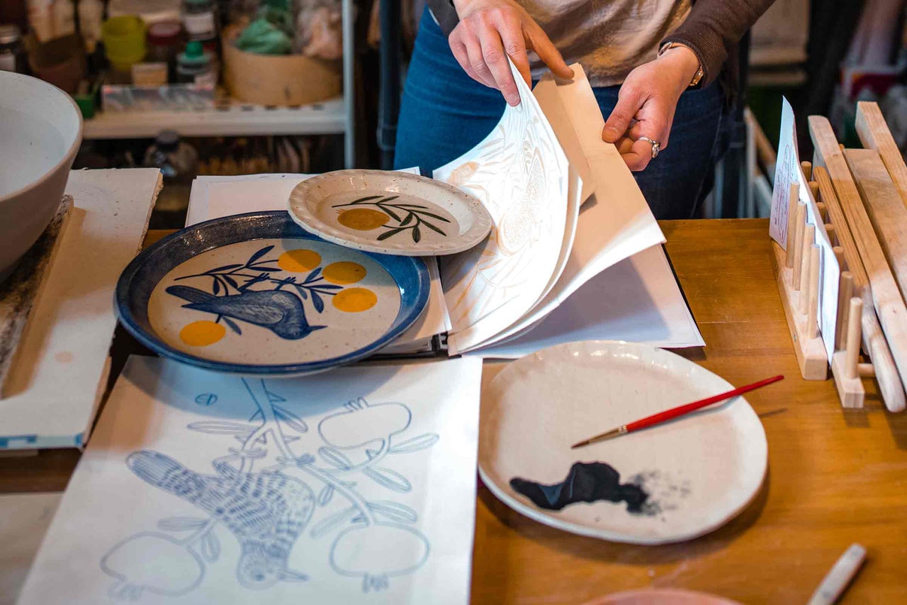 Scenă dintr-un atelier de ceramică cu farfurii, mostre de design și pensule