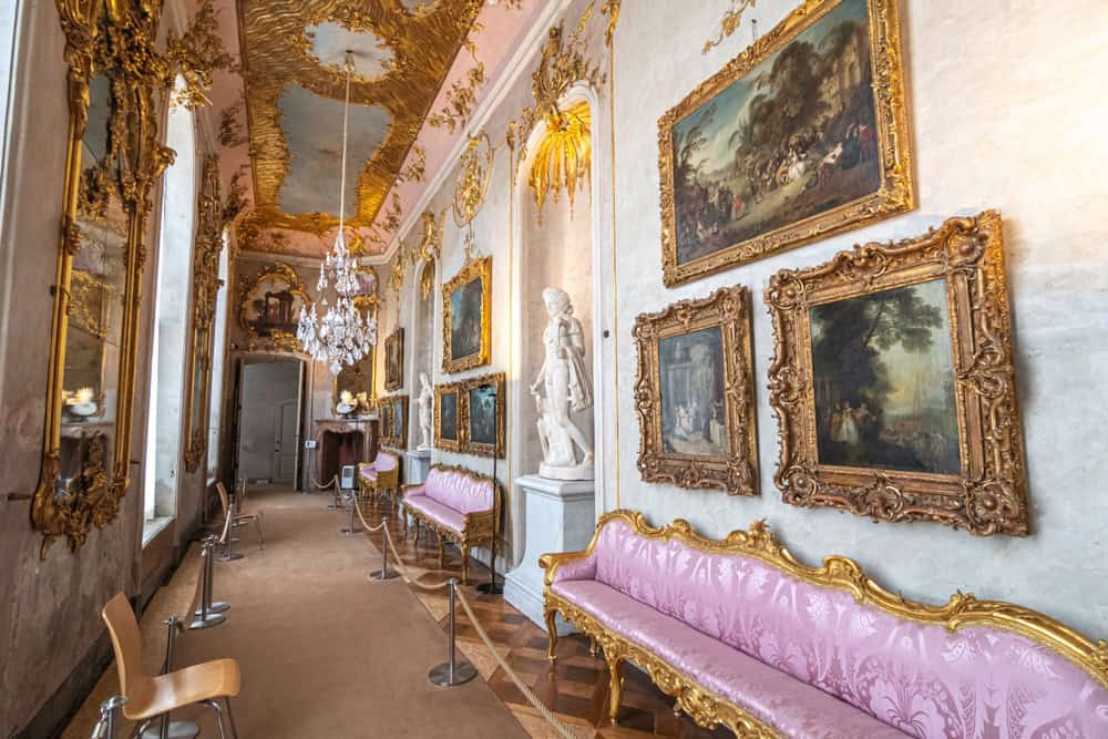 Interiorul unui coridor decorat cu picturi, statui și locuri de stat