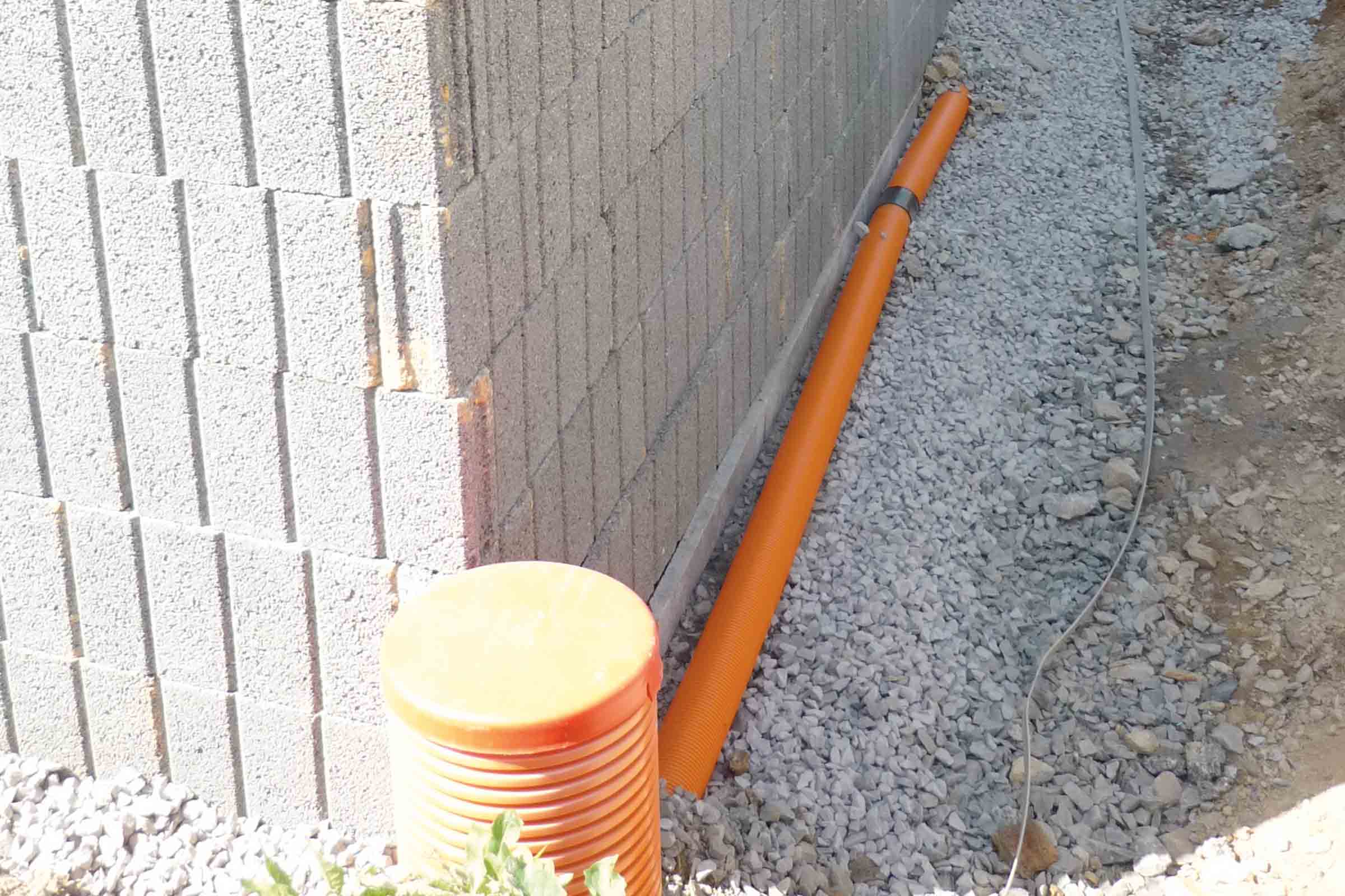 Scenă cu zid, conductă de drenaj și strat de pietriș pentru evacuarea apei