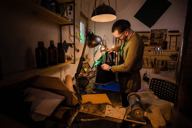 Un meșter lucrează la un sac din piele în atelierul său.