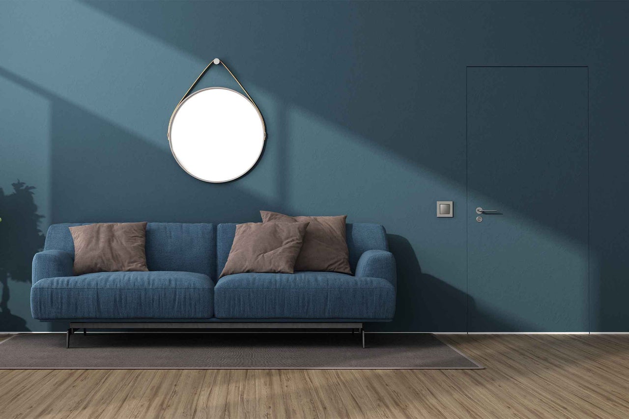 Cameră de zi cu canapea albastră, oglindă rotundă și podea din lemn