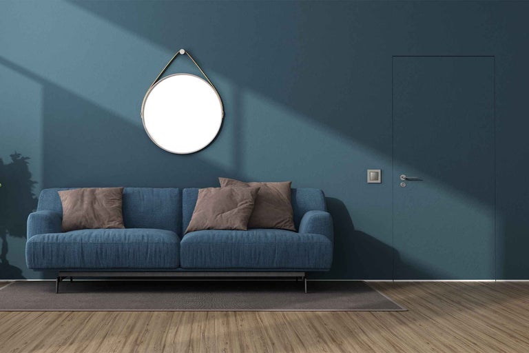 Cameră de zi cu canapea albastră, oglindă rotundă și podea din lemn